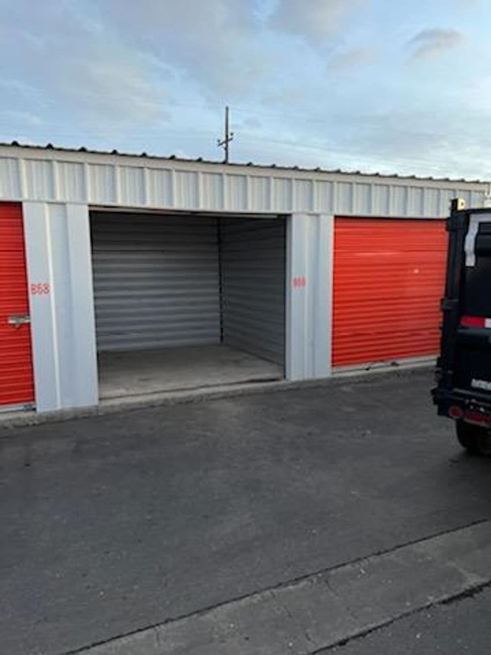 Storage units with orange and gray doors, showcasing empty space in one unit.