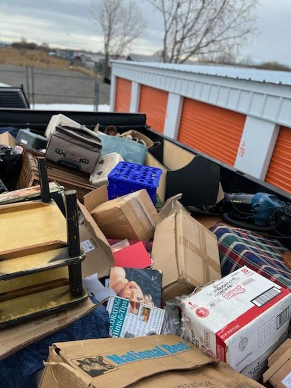 Cluttered storage area filled with boxes, furniture, and miscellaneous items.