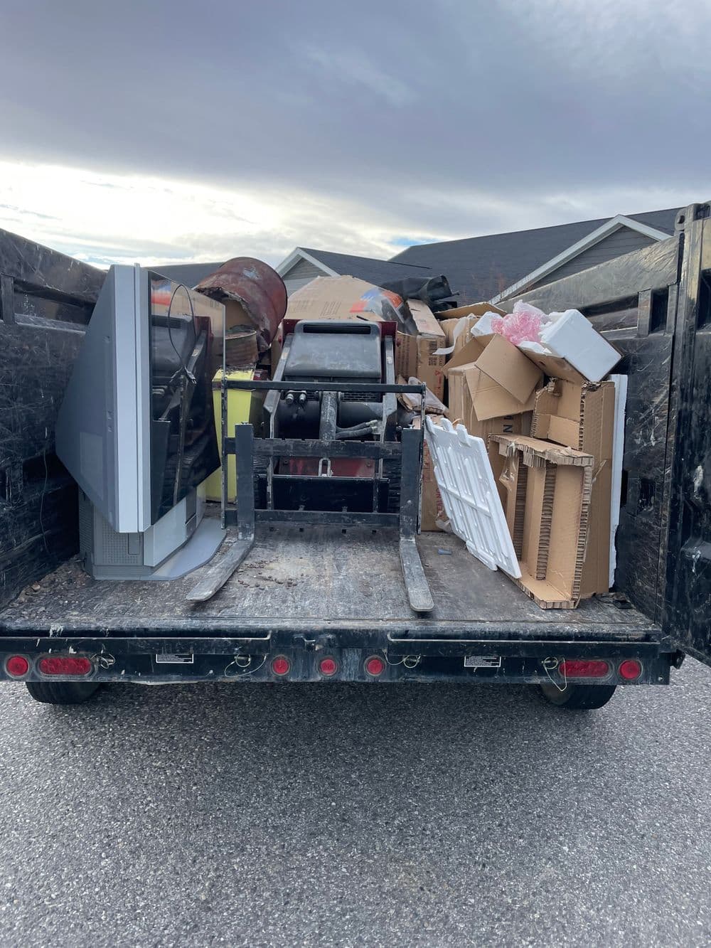 Dump truck filled with assorted junk, including old furniture, boxes, and a TV.