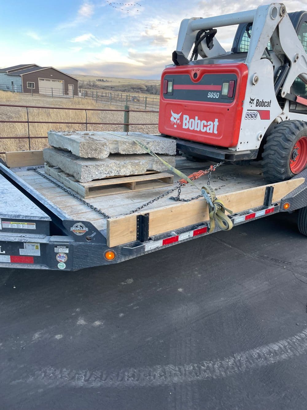 Bobcat 5650 skid steer loader on a trailer with concrete blocks and wooden supports.